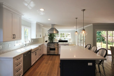 Photo of a large modern l-shaped open plan kitchen in Los Angeles with a farmhouse sink, shaker cabinets, white cabinets, quartz benchtops, grey splashback, mosaic tile splashback, stainless steel appliances, medium hardwood floors and with island.