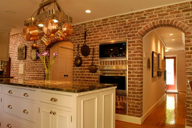 Elegant u-shaped medium tone wood floor enclosed kitchen photo in Los Angeles with an island, recessed-panel cabinets, white cabinets, granite countertops, gray backsplash, ceramic backsplash, stainless steel appliances and a farmhouse sink