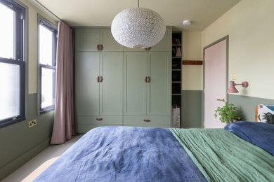 Photo of a medium sized master bedroom in London with green walls, carpet, no fireplace and beige floors.