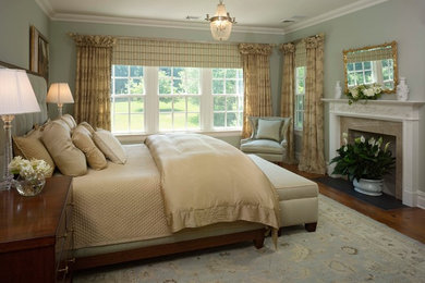 Mid-sized elegant master medium tone wood floor and brown floor bedroom photo in New York with blue walls, a standard fireplace and a tile fireplace