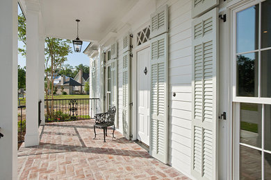Photo of a traditional verandah in New Orleans with brick pavers and a roof extension.