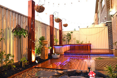 Design ideas for a mid-sized asian backyard and ground level deck in Sydney with with privacy feature and no cover.