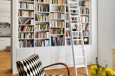 Inspiration for a mid-sized traditional loft-style living room in Other with a library, green walls, light hardwood floors, no fireplace and no tv.