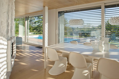 Immagine di una grande sala da pranzo aperta verso il soggiorno minimal con parquet chiaro, camino classico, cornice del camino in pietra e soffitto in legno