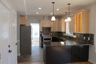 This is an example of a mid-sized contemporary u-shaped eat-in kitchen in Baltimore with an undermount sink, shaker cabinets, quartz benchtops, glass tile splashback, stainless steel appliances and vinyl floors.