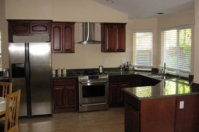 Inspiration for a large timeless u-shaped light wood floor and beige floor open concept kitchen remodel in San Francisco with raised-panel cabinets, red cabinets, quartz countertops, stainless steel appliances and a peninsula