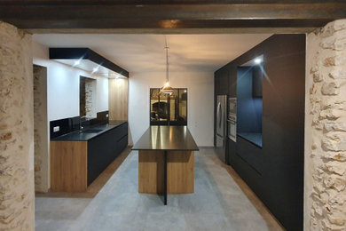 他の地域にある高級な広いコンテンポラリースタイルのおしゃれなキッチン (アンダーカウンターシンク、フラットパネル扉のキャビネット、黒いキャビネット、御影石カウンター、黒いキッチンパネル、ガラス板のキッチンパネル、パネルと同色の調理設備、セメントタイルの床、グレーの床、黒いキッチンカウンター) の写真