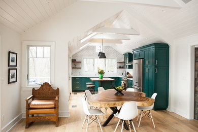 Mid-sized country u-shaped light wood floor and brown floor open concept kitchen photo with an undermount sink, shaker cabinets, green cabinets, quartz countertops, white backsplash, subway tile backsplash, stainless steel appliances, an island and white countertops