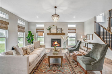 Example of a large country light wood floor living room design in Columbus with white walls, a standard fireplace and a shiplap fireplace