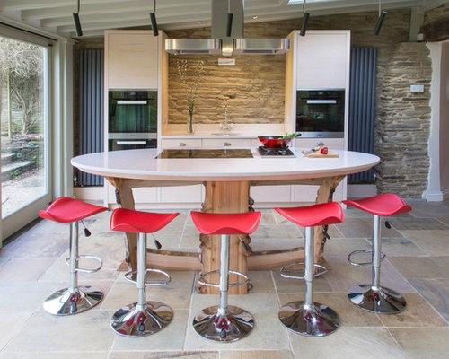 Design ideas for a small modern galley kitchen/diner in Cornwall with a single-bowl sink, flat-panel cabinets, light wood cabinets, engineered stone countertops, stainless steel appliances, an island and slate flooring.