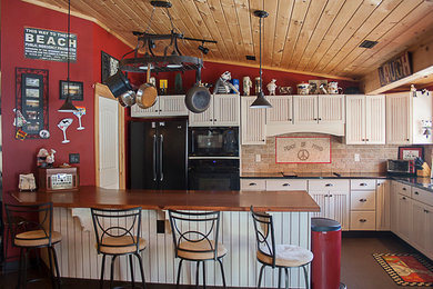 Mid-sized cottage l-shaped ceramic tile and brown floor open concept kitchen photo in New York with an undermount sink, louvered cabinets, white cabinets, quartzite countertops, beige backsplash, stone tile backsplash, black appliances and a peninsula