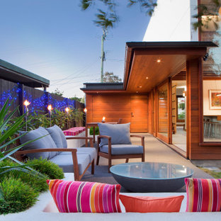 Photo of a mid-sized contemporary backyard patio in Brisbane with a fire feature, gravel and an awning.
