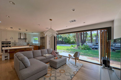 Großes, Offenes Modernes Wohnzimmer ohne Kamin mit Hausbar, weißer Wandfarbe, hellem Holzboden, freistehendem TV und braunem Boden in San Francisco
