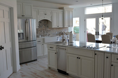 Inspiration for a large transitional light wood floor and brown floor eat-in kitchen remodel in Other with a farmhouse sink, raised-panel cabinets, white cabinets, marble countertops, multicolored backsplash, subway tile backsplash, stainless steel appliances and an island