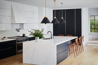 This is an example of an expansive modern kitchen in New York with flat-panel cabinets, blue cabinets, quartz benchtops, white splashback, engineered quartz splashback, with island and white benchtop.