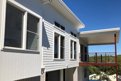 This is an example of a beach style two-storey grey house exterior in Sunshine Coast with a metal roof.