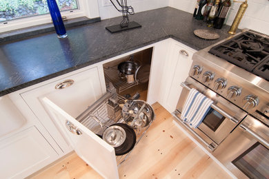 Inspiration for a large transitional l-shaped open plan kitchen in San Francisco with a farmhouse sink, shaker cabinets, white cabinets, soapstone benchtops, white splashback, ceramic splashback, stainless steel appliances, light hardwood floors and with island.