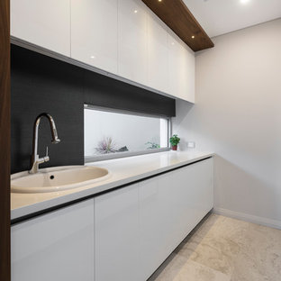 Photo of a large contemporary galley separated utility room in Perth with a built-in sink, recessed-panel cabinets, white cabinets, engineered stone countertops, grey walls, a stacked washer and dryer, grey floors, white worktops and limestone flooring.