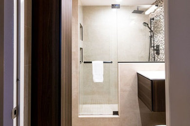 Inspiration for a mid-sized contemporary 3/4 beige tile, black tile, black and white tile, white tile and porcelain tile limestone floor and beige floor alcove shower remodel in New York with flat-panel cabinets, black cabinets, a one-piece toilet, beige walls, an integrated sink, solid surface countertops and a hinged shower door