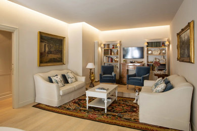 Imagen de sala de estar con biblioteca cerrada tradicional de tamaño medio sin chimenea con paredes beige, suelo de madera clara, televisor colgado en la pared, bandeja y alfombra