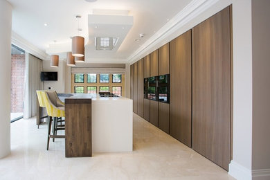 Design ideas for a large contemporary galley kitchen/diner in West Midlands with an integrated sink, flat-panel cabinets, medium wood cabinets, composite countertops, black appliances, limestone flooring, an island and white floors.