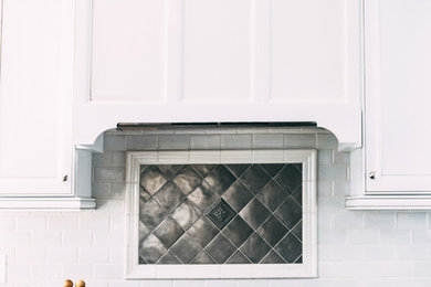 Inspiration for a transitional u-shaped brown floor and dark wood floor eat-in kitchen remodel in New York with recessed-panel cabinets, white cabinets, granite countertops, multicolored backsplash, glass tile backsplash, stainless steel appliances, an island, multicolored countertops and an undermount sink