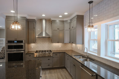Example of a large urban u-shaped medium tone wood floor and brown floor eat-in kitchen design in Other with an undermount sink, gray cabinets, granite countertops, white backsplash, stainless steel appliances, an island, shaker cabinets and subway tile backsplash
