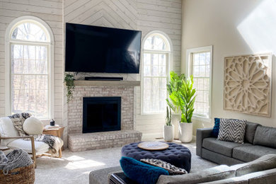 Example of a large cottage open concept carpeted, beige floor, vaulted ceiling and shiplap wall living room design in New York with beige walls, a standard fireplace, a brick fireplace and a wall-mounted tv