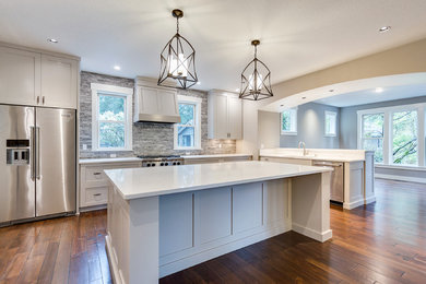 Large country u-shaped eat-in kitchen in Salt Lake City with an undermount sink, recessed-panel cabinets, grey cabinets, quartz benchtops, grey splashback, stone tile splashback, stainless steel appliances, dark hardwood floors, with island, brown floor and white benchtop.