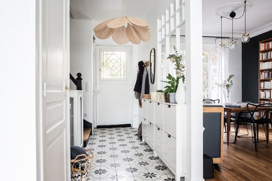 Aménagement d'une petite entrée contemporaine avec un couloir, un mur blanc, une porte simple, une porte blanche et un sol multicolore.