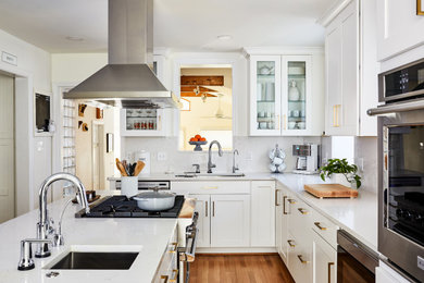 Eat-in kitchen - mid-sized transitional medium tone wood floor eat-in kitchen idea in DC Metro with white cabinets, white backsplash, stainless steel appliances, an island and white countertops
