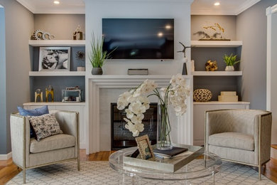 Example of a mid-sized classic enclosed medium tone wood floor living room design in New York with gray walls, a standard fireplace, a stone fireplace and a wall-mounted tv