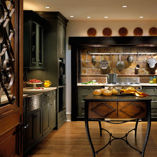Große Urige Küche in L-Form mit Vorratsschrank, Landhausspüle, Schrankfronten mit vertiefter Füllung, grünen Schränken, Kalkstein-Arbeitsplatte, bunter Rückwand, Rückwand aus Steinfliesen, Elektrogeräten mit Frontblende, braunem Holzboden und Kücheninsel in Chicago