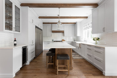 Large country medium tone wood floor and exposed beam eat-in kitchen photo in Montreal with a farmhouse sink, shaker cabinets, gray cabinets, marble countertops, white backsplash, porcelain backsplash, stainless steel appliances, an island and white countertops