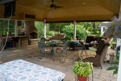 Inspiration for a huge rustic backyard stone patio kitchen remodel in Other with a pergola