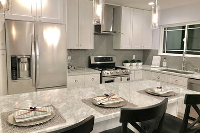 Mid-sized transitional l-shaped enclosed kitchen photo in Los Angeles with a double-bowl sink, shaker cabinets, white cabinets, quartz countertops, metallic backsplash, mosaic tile backsplash, stainless steel appliances and an island
