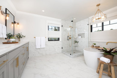 This is an example of a large classic ensuite bathroom in San Francisco with recessed-panel cabinets, grey cabinets, a freestanding bath, a corner shower, a one-piece toilet, white tiles, ceramic tiles, grey walls, ceramic flooring, a submerged sink, engineered stone worktops, white floors, a hinged door, white worktops, an enclosed toilet, double sinks and a built in vanity unit.