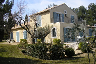 Idées déco pour une grande façade de maison jaune campagne en stuc à un étage avec un toit à deux pans et un toit en tuile.