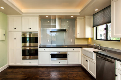 Inspiration for a modern l-shaped dark wood floor eat-in kitchen remodel in Santa Barbara with a farmhouse sink, white cabinets, stainless steel appliances and no island