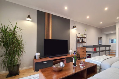 Imagen de salón gris y negro actual pequeño con paredes negras, suelo de madera en tonos medios, televisor independiente y suelo marrón