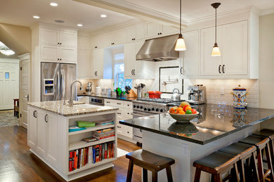 Photo of a traditional l-shaped eat-in kitchen in Seattle with a farmhouse sink, shaker cabinets, white cabinets, granite benchtops, white splashback, ceramic splashback and stainless steel appliances.