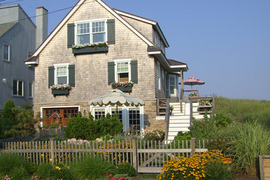 Large beach style gray two-story wood exterior home photo in New York with a shingle roof