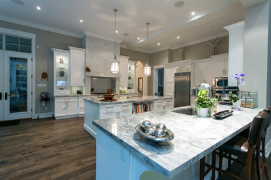 Inspiration for a large transitional l-shaped dark wood floor and brown floor open concept kitchen remodel in Toronto with a single-bowl sink, recessed-panel cabinets, white cabinets, granite countertops, gray backsplash, glass tile backsplash, stainless steel appliances and two islands