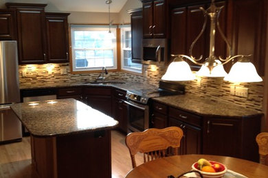 Eat-in kitchen - mid-sized transitional l-shaped light wood floor and beige floor eat-in kitchen idea in St Louis with an undermount sink, raised-panel cabinets, dark wood cabinets, granite countertops, multicolored backsplash, matchstick tile backsplash, stainless steel appliances, an island and multicolored countertops