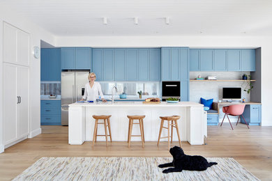 Inspiration for a mid-sized contemporary galley open plan kitchen in Melbourne with a double-bowl sink, shaker cabinets, blue cabinets, quartz benchtops, glass sheet splashback, stainless steel appliances, medium hardwood floors, with island, brown floor and white benchtop.