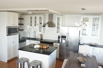 Example of a mid-sized farmhouse l-shaped medium tone wood floor eat-in kitchen design in Chicago with an undermount sink, shaker cabinets, white cabinets, granite countertops, white backsplash, ceramic backsplash, stainless steel appliances and an island