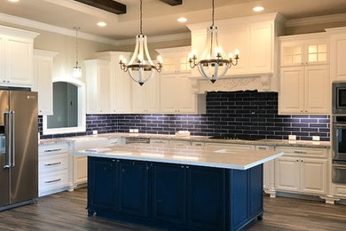 Open concept kitchen - large transitional l-shaped laminate floor and gray floor open concept kitchen idea in Austin with a farmhouse sink, raised-panel cabinets, white cabinets, quartzite countertops, blue backsplash, subway tile backsplash, stainless steel appliances, an island and white countertops