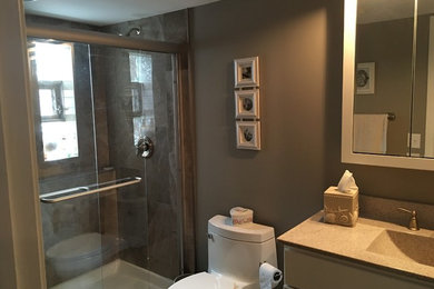 Mid-sized elegant 3/4 multicolored tile and stone slab alcove shower photo in Chicago with flat-panel cabinets, white cabinets, a one-piece toilet, brown walls, an integrated sink, granite countertops and a hinged shower door