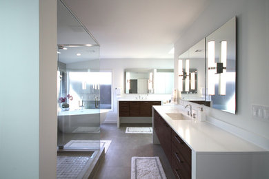 Design ideas for a modern master bathroom in Dallas with flat-panel cabinets, medium wood cabinets, a freestanding tub, a double shower, a two-piece toilet, brown tile, porcelain tile, white walls, porcelain floors, an undermount sink, solid surface benchtops, brown floor and a hinged shower door.