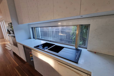 Photo of a large modern l-shaped kitchen in Melbourne with a double-bowl sink, white cabinets, quartz benchtops, engineered quartz splashback, dark hardwood floors, with island, brown floor and white benchtop.